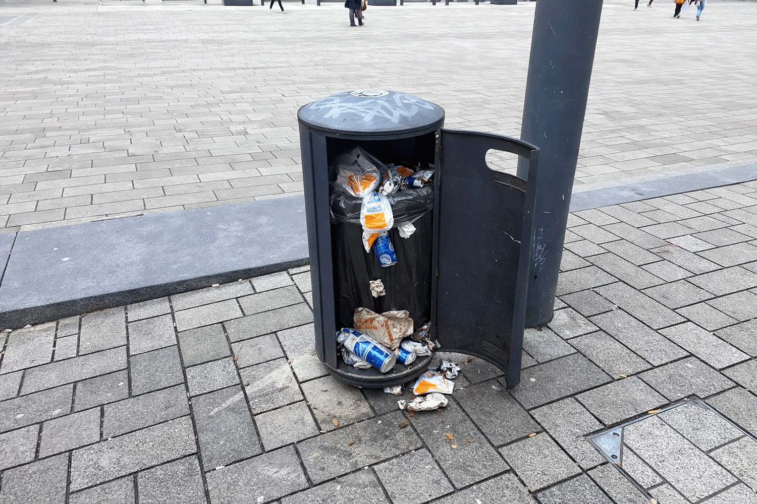 Müll liegt vor offenem Mülleimer